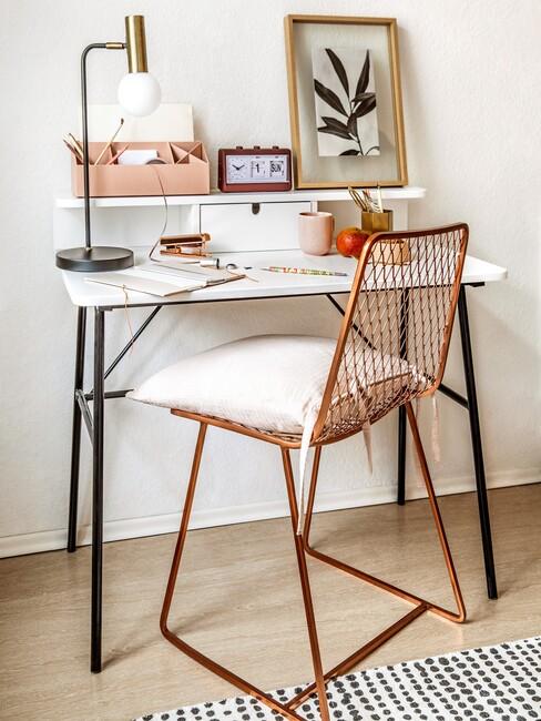 brons kleur stoel aan een wit bureau met lamp en accessoires