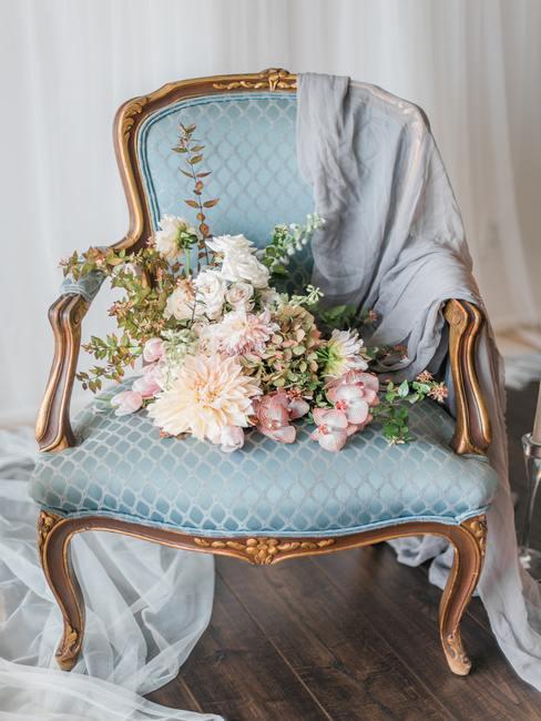 Stijlvolle stoel met een blauwe hoes met een boeket bloemen op de zitting