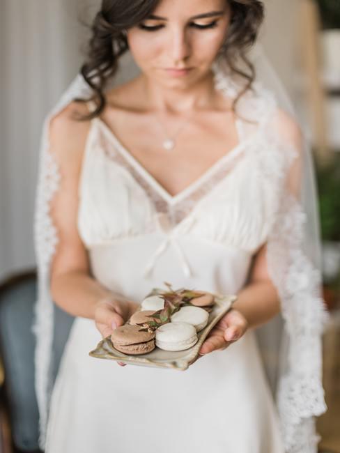 Een vrouw in een trouwjurk met een cadeau voor de gasten in haar hand