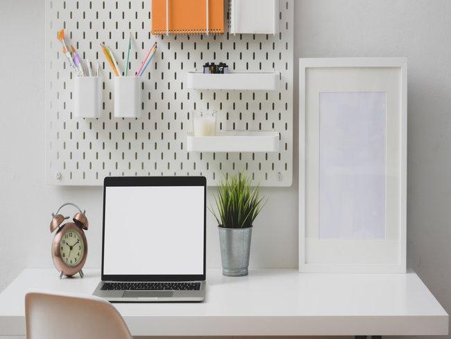 Home office met laptop en wandrek met bureaubenodigdheden voorjaarsschoonmaak