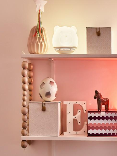 Close-up roze meisjeskamer met accessoires en witte beerlamp