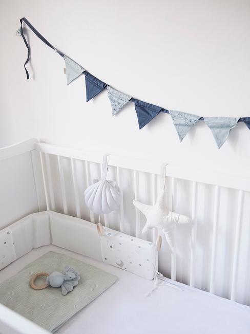 Wit babybedje met blauwe wanddecoratie