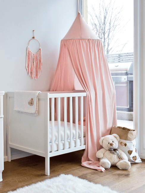 Complete babykamer: wit kinderbedje met roze klamboe en pluchen knuffels