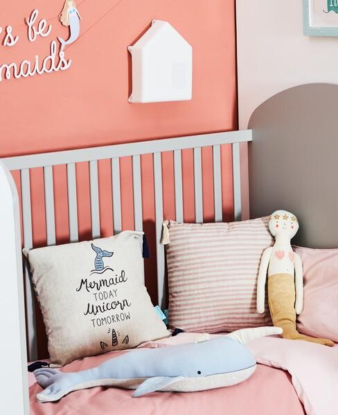 grijs baby bed met een zeemeermin en een roze muur