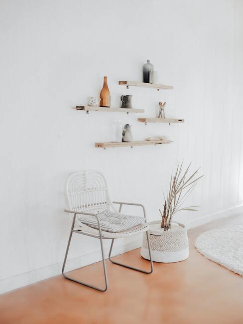 Witte stoel naast een pot met plant en witte planken op witte muur