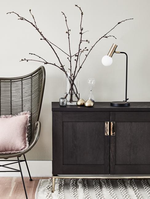 Sideboard van donker hout naast een fauteuil met roze sierkussen