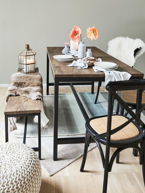 Houten eettafel met stoelen en zitbank met plaid