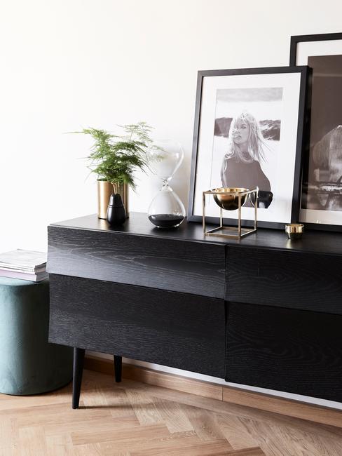 Zwarte sideboard met ingeliste print en goudkleurige vaas met bloemen