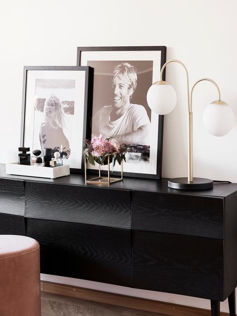 Zwarte sideboard met ingeliste print en goudkleurige tafellamp