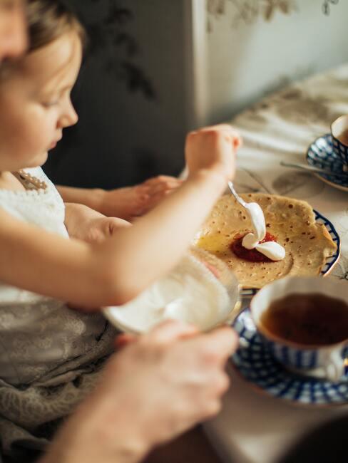 Een meisje maakt pannenkoeken klaar voor het avondeten