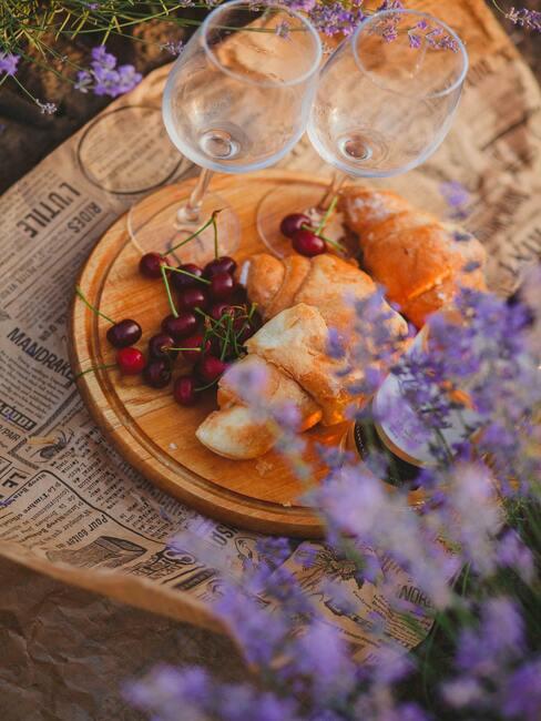 Kaasplankje met kersen op tafel met een vaas met bloemen en wijnglazen