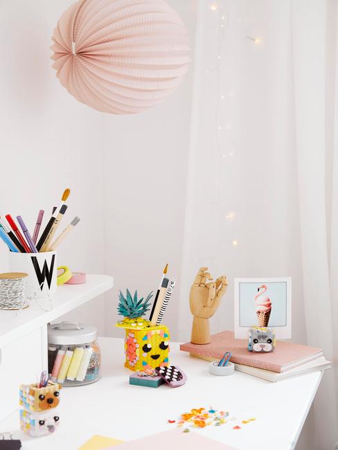 Een wit bureau met veel kleurrijke schrijf- en tekenaccessoires