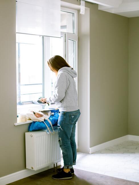 De vrouw ruimt na het schilderen de kamer op