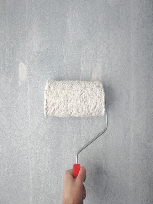 Verf de muur grijs met een roller
