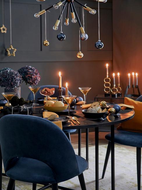 Kerstdecoratie in een marineblauwe woonkamer met blauwe stoelen en een zwarte tafel
