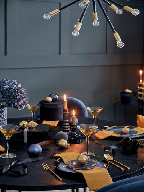 Gedekte tafel in blauw en goud kleur met kaarsen en gele servetten