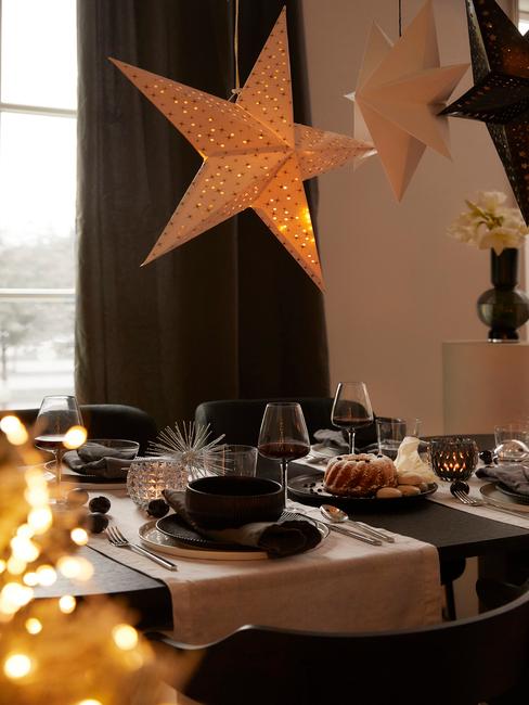 Kerst checklist: gedekte tafel met serviesset in zwart, witte tafelloper en kerstdecoratie
