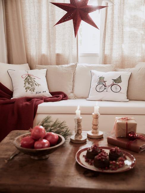 Kerstdecoratie van de woonkamer in wit en rood met kaarsen en sierkussens