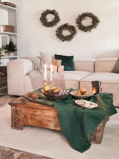 Dobbelspel kerst Woonkamer in het wit met een comfortabele bank en sierkussens en een witte salontafel met kaarsen en kerstversiering