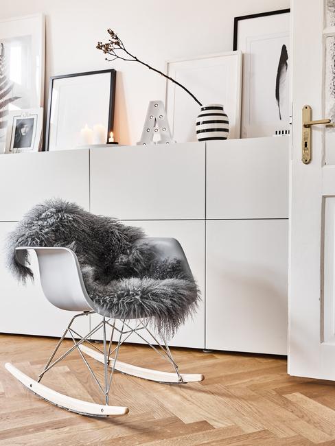Dressoir in moderne stijl in wit naast een schommelstoel in wit met schapenvacht in grijs
