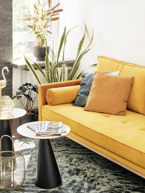Zitbank in geel met sierkussens en glazen bijzettafel