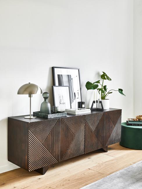 donkerhouten dressoir met zilveren lamp en kamerplant