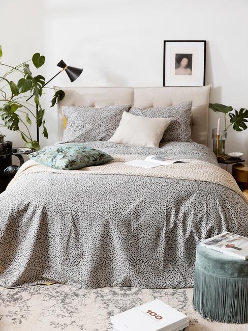 grijs dekbed met zwarte lamp en blauwe poef