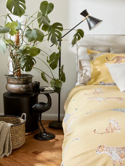 geel dekbed met zwarte lamp en plant