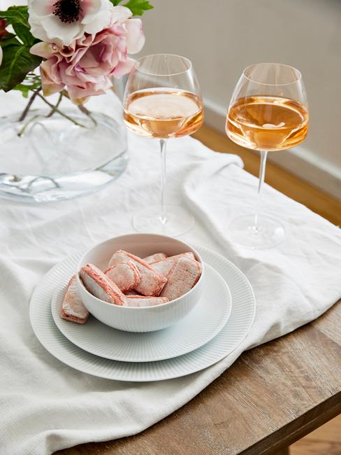 Een wit tafelkleed met wit serviesgoed en bestekset in goud kleur