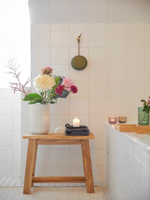 Witte vaas met bloemen op de houten kruk