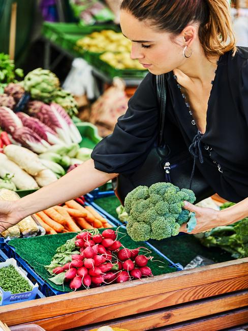 Vrouw op de markt kiest groente uit