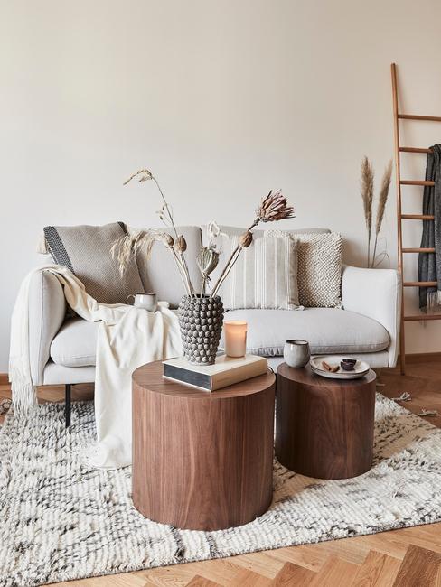Comfortabele beige bank met sierkussens naast een houten salontafel met kaarsen