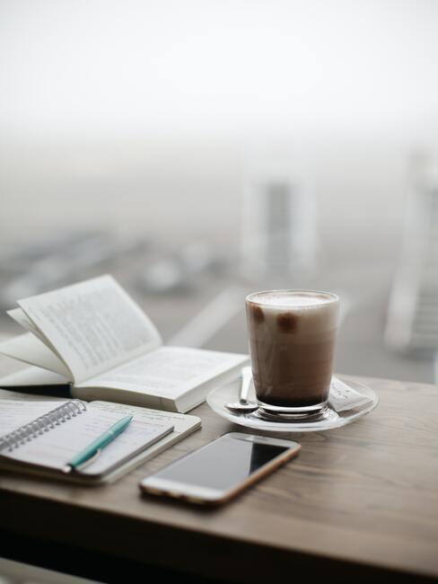 Kop koffie en notitieboekje op werkplek met uitzicht