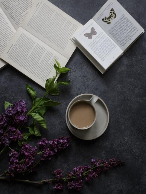Kopje koffie met schoteltje naast een boek