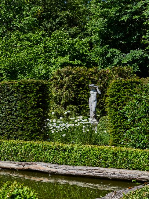 sculptuur in een tuin vol bomen en bloemen