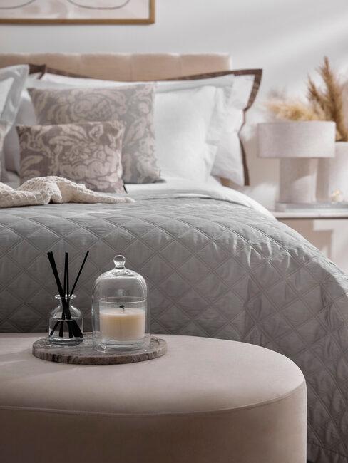 een tweepersoonsbed met grijze plaid