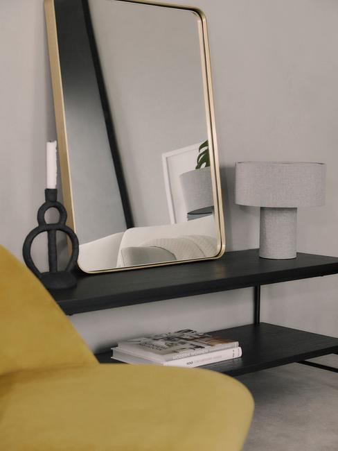 Zwarte metalen sideboard naast een fauteuil in geel