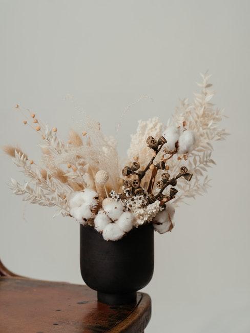 zwarte vaas van keramiek op een stoel met een boeket gedroogde bloemen