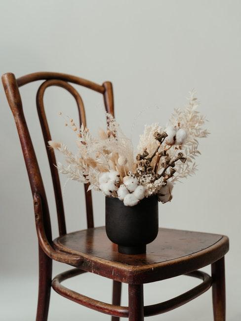 zwarte vaas van keramiek op stoel met droogbloemen