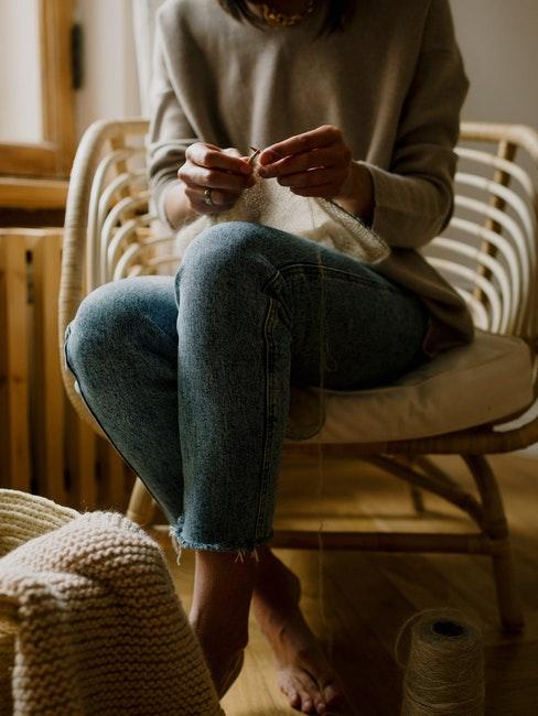 vrouw in een fauteuil breit een trui