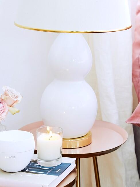 witte lamp met gouden accenten op een pastel roze bijzettafel