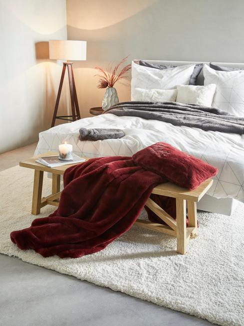 Bed met houten bank en rode deken