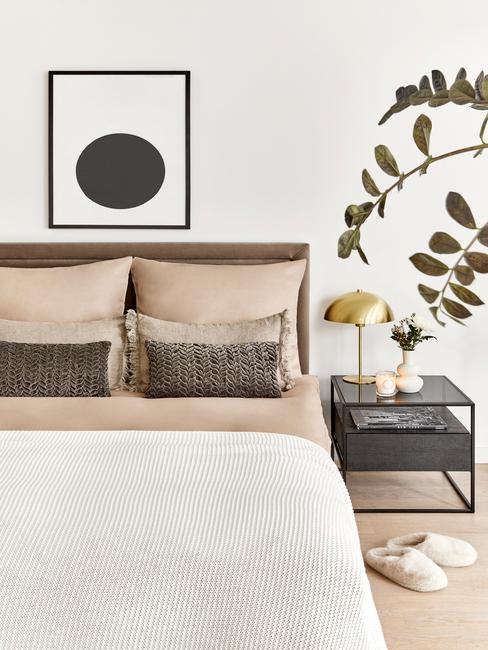 beige bed met plant en fotolijst