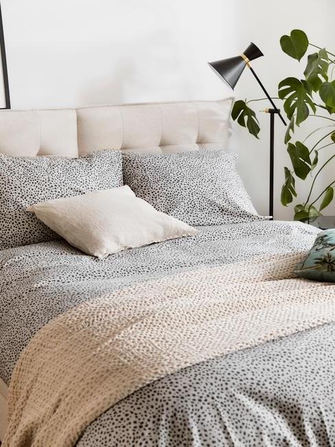 toupe bed met grijze deken en zwarte lamp