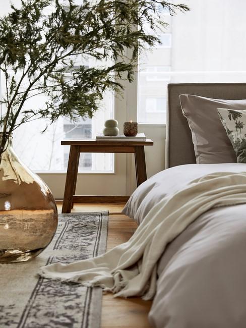 grijs dekbed met houten tafel en plant