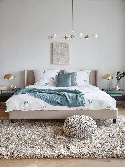 beige bed met wit dekbed en beige poef