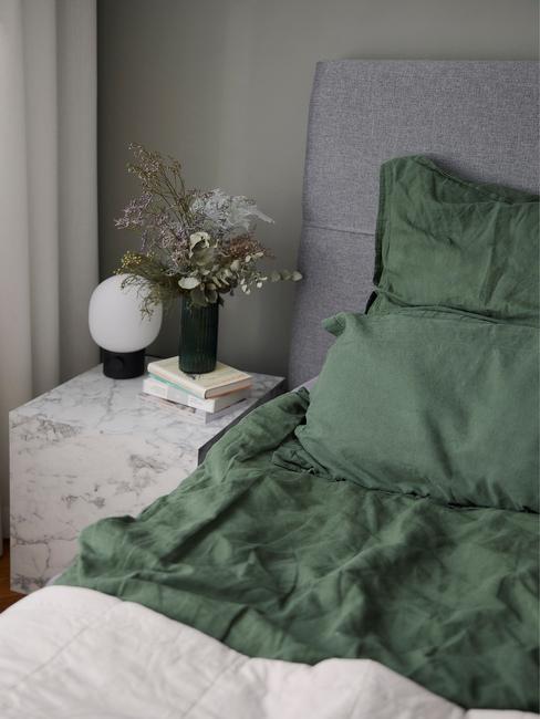 grijs bed met groen dekbed en marmere tafel