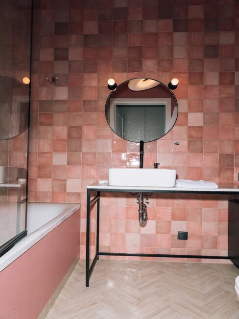 roze tegels met zwart meubel en ronde spiegel