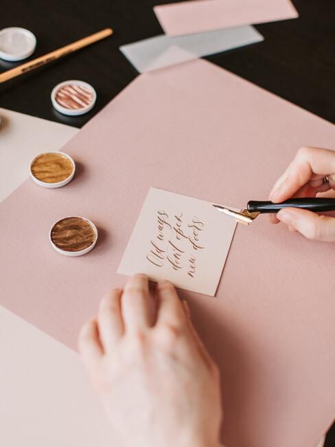 roze bureau met wit briefje met zwarte inktpen