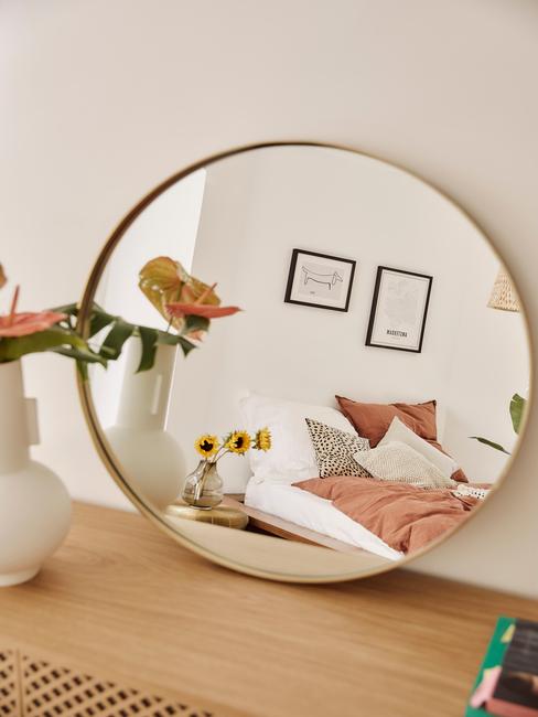 gouden ronde spiegel op houten kast
